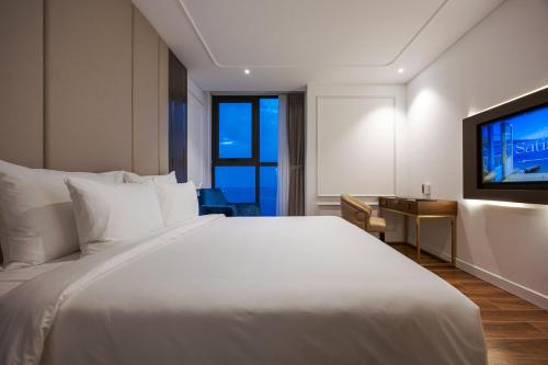a bedroom with a large white bed and a television at OYSTER BAY HOTEL VUNG TAU in Vung Tau