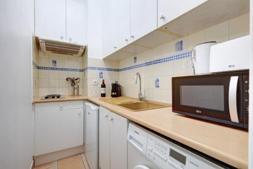 une cuisine avec des armoires blanches et un micro-ondes dans l'établissement 5018 Suite Murillo - Nice apartment Champs-Élysées, à Paris