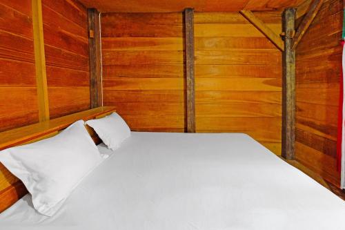 a bed in a room with wooden walls at Hotel O Tatto Bara Homestay Near Tongkonan Payung Pangden in Madandan