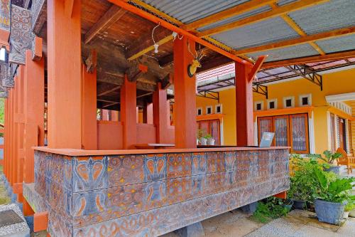 an outside view of a building with orange pillars at Hotel O Tatto Bara Homestay Near Tongkonan Payung Pangden in Madandan