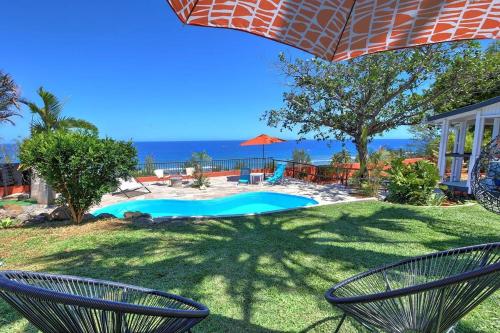 una piscina con dos sillas y una sombrilla en Villa Vue-Belle, en Saint-Paul