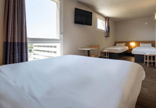 a hotel room with a large bed and a window at B&B HOTEL Grenoble Centre Alpexpo in Grenoble