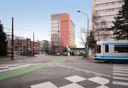 a train on a city street with a building at B&B HOTEL Grenoble Centre Alpexpo in Grenoble