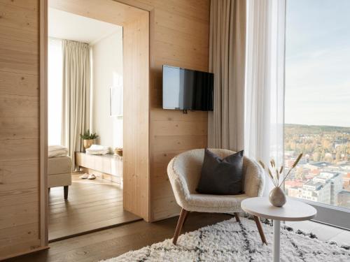 a living room with a chair and a tv at The Wood Hotel by Elite in Skellefteå