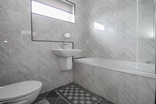a bathroom with a white toilet and a sink at Greenside Getaway in Newarthill