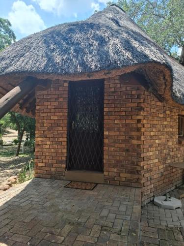 a brick building with a thatched roof with a door at Jabula Kruger Safari Lodge in Marloth Park