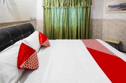 a bedroom with a bed with red pillows on it at Hotel O Manisee 1 Homestay Syariah in Tanjunguma