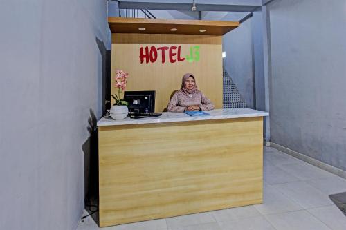 a woman sitting at a counter in a hotel room at Hotel O J3 in Labuan Lombok