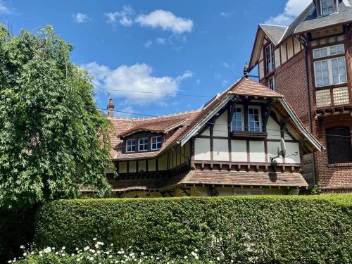 une vieille maison avec une haie devant elle dans l'établissement Houlgate appartement, à Houlgate