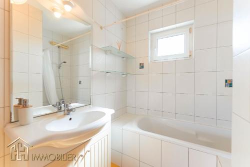 La salle de bains blanche est pourvue d'un lavabo et d'une baignoire. dans l'établissement Appartement L'Orient - Parking, à Colmar