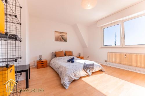 une chambre avec un lit et un bureau et deux fenêtres dans l'établissement Appartement L'Orient - Parking, à Colmar