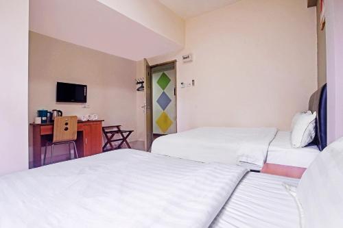 a room with two beds and a desk with a television at Hotel O Night Queen salak Tinggi in Sepang