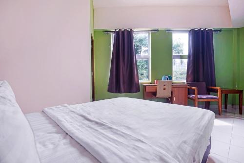 a bedroom with a bed and a desk and window at Hotel O Night Queen salak Tinggi in Sepang