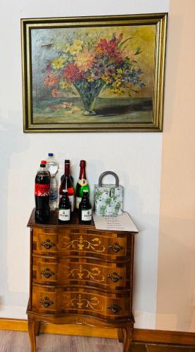 a painting above a dresser with bottles on it at Maja Ferienwohnung in Goddelsheim