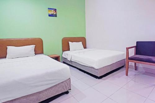 a room with two beds and a chair in it at Hotel O Night Queen salak Tinggi in Sepang