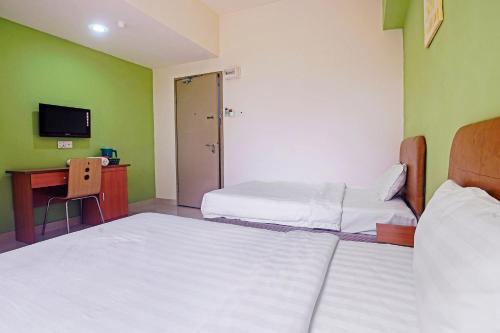 a room with two beds and a desk and a television at Hotel O Night Queen salak Tinggi in Sepang