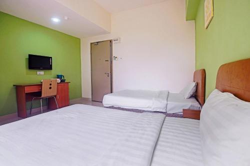 a room with two beds and a desk and a television at Hotel O Night Queen salak Tinggi in Sepang