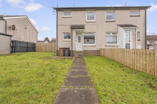 a house with a fence and a grass yard at Greenside Getaway in Newarthill