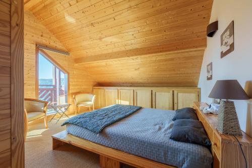 une chambre avec un lit et un plafond en bois dans l'établissement Le Chalet du Xetté - Sauna et vue montagne, à Gérardmer