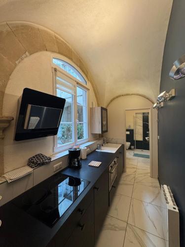 une cuisine avec un grand évier et une grande fenêtre dans l'établissement Ancien Couvent au Cœur du vieux Valence, à Valence