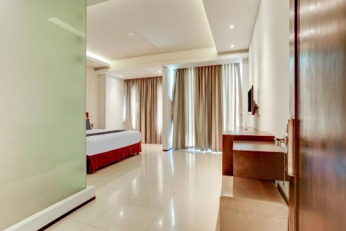 a hotel room with a bed and a desk at Collection O Legian Near Pantai Kuta Formerly Premium Legian in Legian