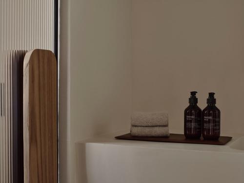 a shelf with three bottles and a towel at Stamna Sifnos a member of Design Hotels in Sifnos