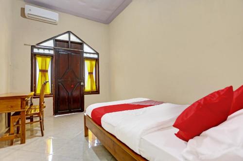a bedroom with a bed and a desk and window at OYO 91261 Cita Suraya Homestay in Banyuwangi