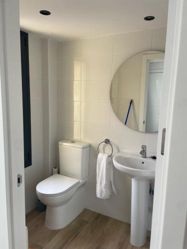 a white bathroom with a toilet and a sink at El Portalet in Montblanc