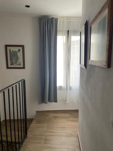 a hallway with a staircase and a window with blue curtains at El Portalet in Montblanc