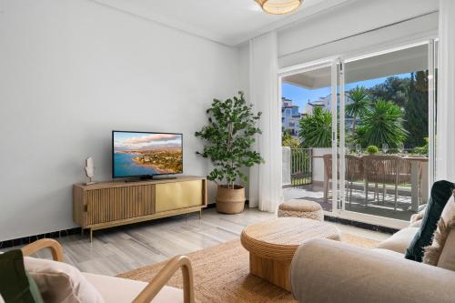 a living room with a flat screen tv on a wooden cabinet at Medina Garden 201 in Marbella