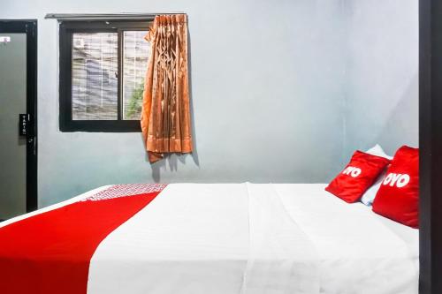 a bedroom with a bed with red pillows and a window at Hotel O 59 Residence in Jakarta