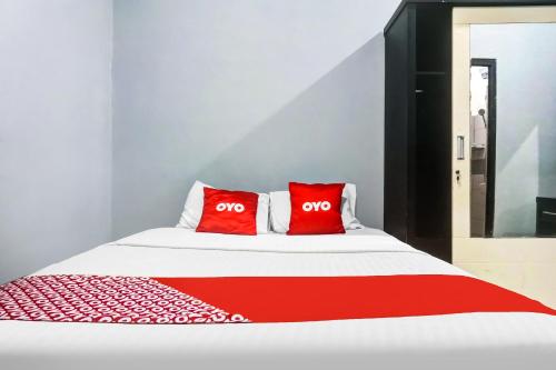 a bed with two red pillows on top of it at Hotel O 59 Residence in Jakarta