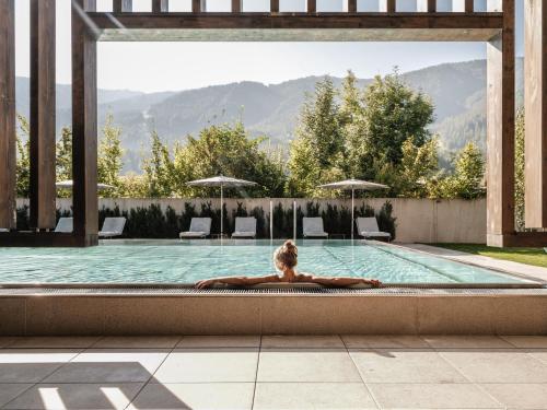 a woman is laying in a swimming pool at Falkensteiner Hotel Kronplatz - The Leading Hotels of the World in Brunico