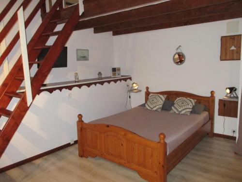 - une chambre avec un lit en bois et un escalier dans l'établissement Le Rayon de Soleil, à Courtils