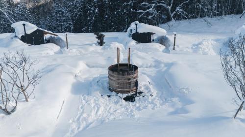 a snow covered yard with a barrel in the snow at Earthboat Hakuba in Hakuba