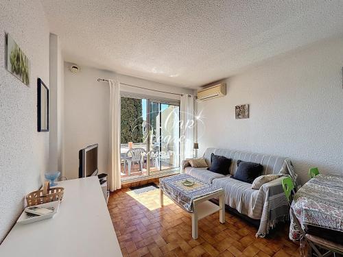 un salon avec un canapé et une table dans l'établissement Appartement T2, 4 personnes terrasse vue mer résidence avec piscine à Pramousquier - LE LAVANDOU, au Lavandou