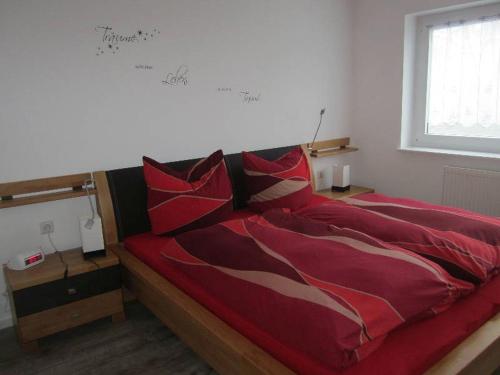 ヘーヘンシュヴァントにあるFerienwohnung Bäumchenの赤い枕が付いた赤いベッド