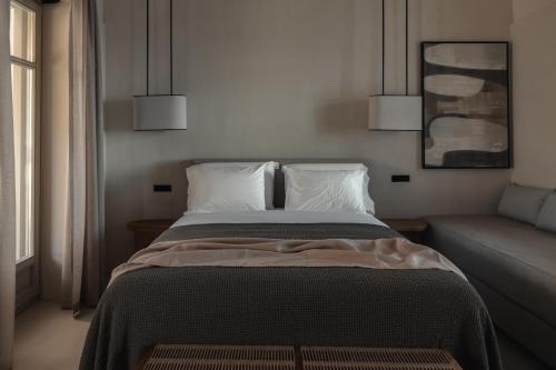 a bedroom with a bed with two pillows and a couch at Stamna Sifnos a member of Design Hotels in Sifnos
