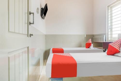 two beds in a room with red and white at OYO 91316 Hh Guest House Makassar in Makassar