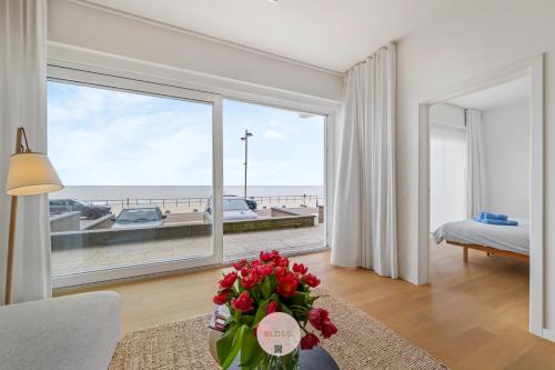 a living room with a large window with a view of the ocean at Osean by BLOSS luxe appartement met frontaal zeezicht, binnenzwembad en parking in Middelkerke