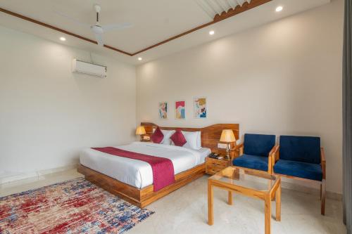 a bedroom with a bed and a blue chair at Corbett Tusker Meadows by White Flower in Rāmnagar