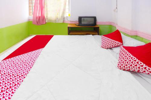 a bedroom with a bed with red and white pillows at Hotel O Kartika Guest House SyariahNearPantai Stres in Jodoh