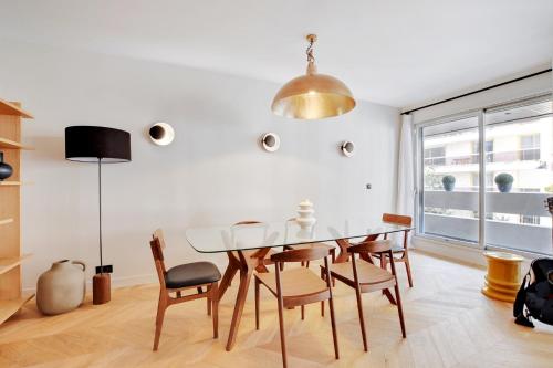 une salle à manger avec une table et des chaises en verre dans l'établissement Magnifique appartement 140 m2 avec terrasse - bail mobilité, à Paris