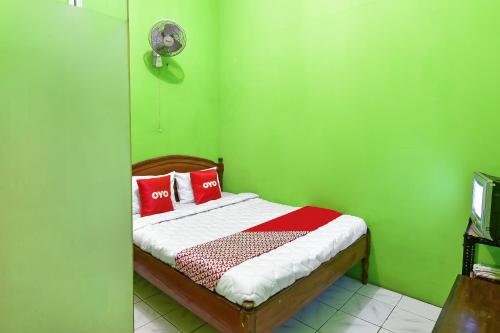 sypialnia z zielonymi ścianami i łóżkiem z czerwonymi poduszkami w obiekcie SPOT ON 91357 Hotel Mulyo w mieście Purwokerto
