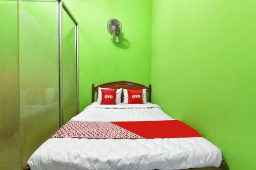 zielony pokój z łóżkiem i dwiema czerwonymi poduszkami w obiekcie SPOT ON 91357 Hotel Mulyo w mieście Purwokerto