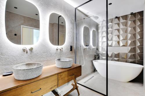 La salle de bains est pourvue de 2 lavabos, d'une baignoire et de miroirs. dans l'établissement Magnifique appartement 140 m2 avec terrasse - bail mobilité, à Paris