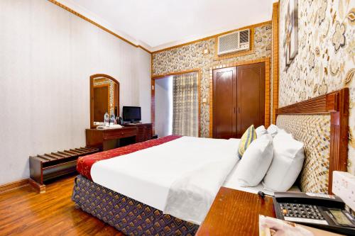 a hotel room with a bed and a desk with a computer at Capital O 125 Moon Plaza Hotel in Manama