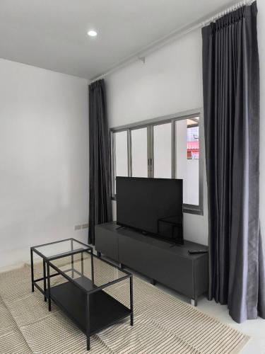 Home Phuket Andaman 3BR في Ban Klang: غرفة معيشة مع تلفزيون وطاولة قهوة زجاجية