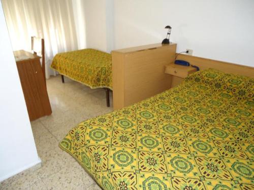 a hotel room with two beds and a yellow and green bedspread at Residència Restaurant Indalo in Andorra la Vella