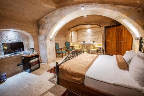 a bedroom with a large bed in a stone room at Caldera Cave Hotel in Uchisar